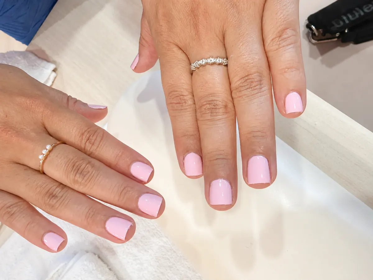 Short natural nails finished in a soft pink Dazzle Dry lacquer at the manicure station