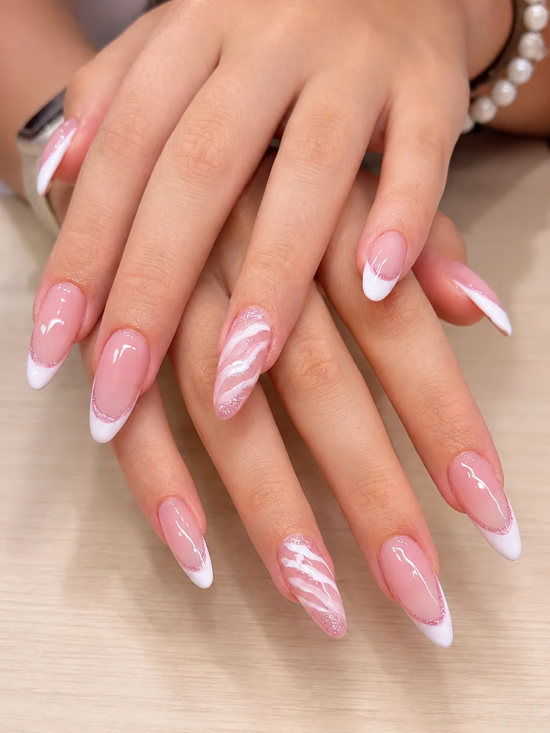 Hands with almond-shaped Russian builder gel nails in soft pink with white French tips and marble nail art
