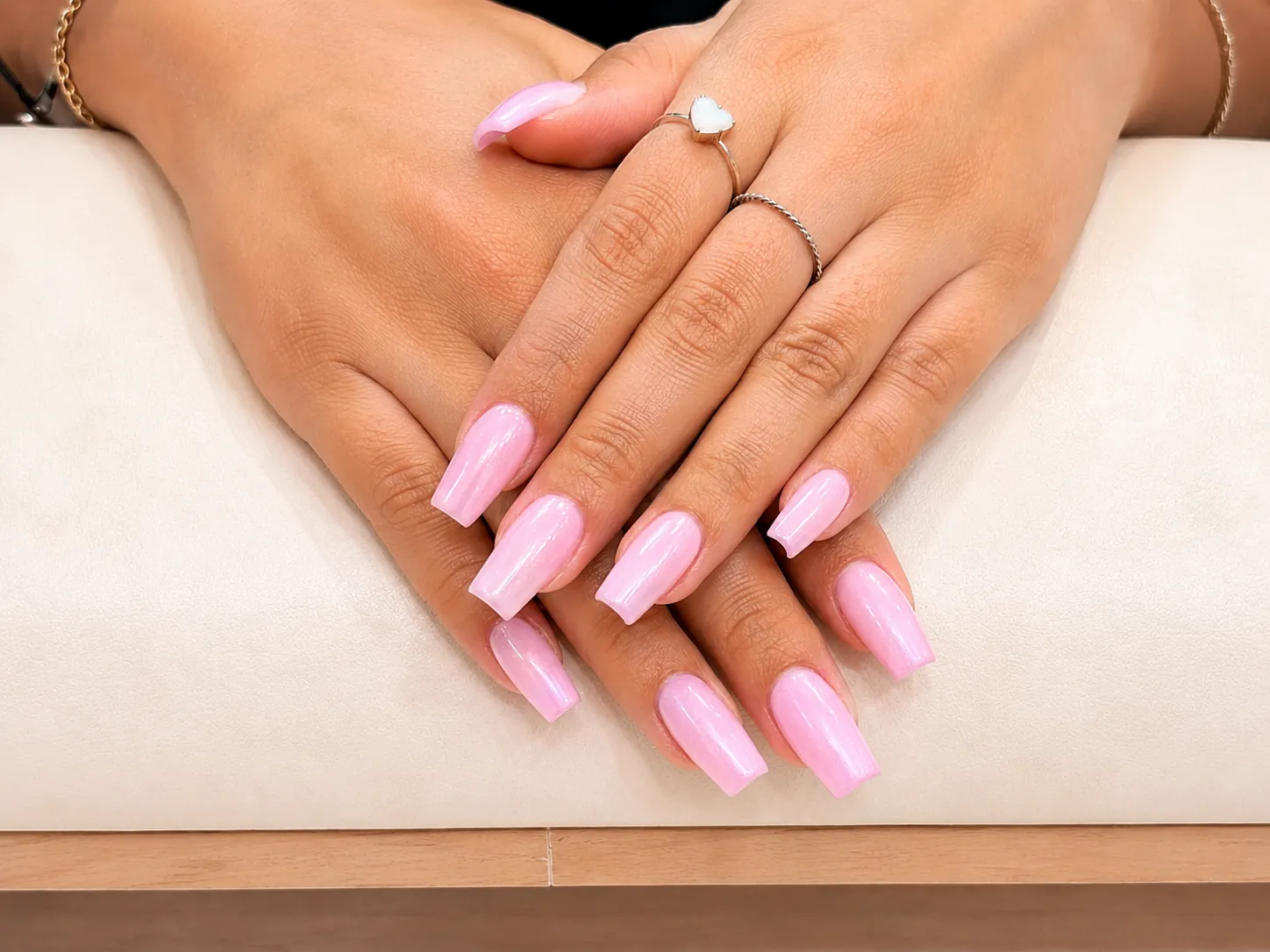 Hands with long square pink pearlescent manicured nails
