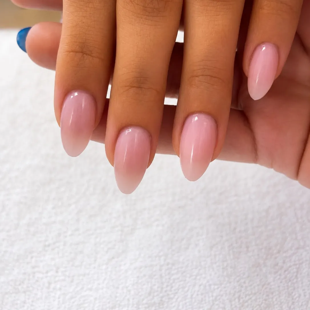Close-up of soft pink almond nails showing the crisp, clean contour where color meets the base of the nail